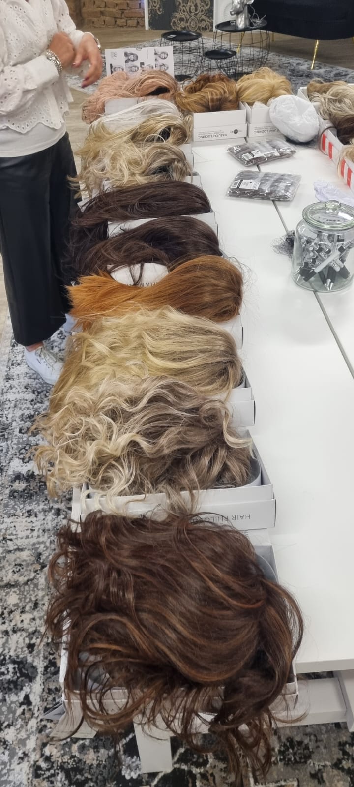 Reihe aus Perücken in verschiedenen Blond- und Brauntönen bei einer Perücken Party auf einem Tisch